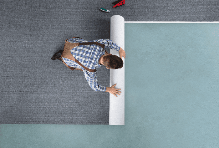 Worker rolls carpet in garage