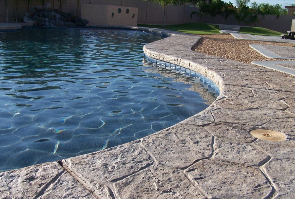 Stamped concrete pool deck surrounding curved swimming pool