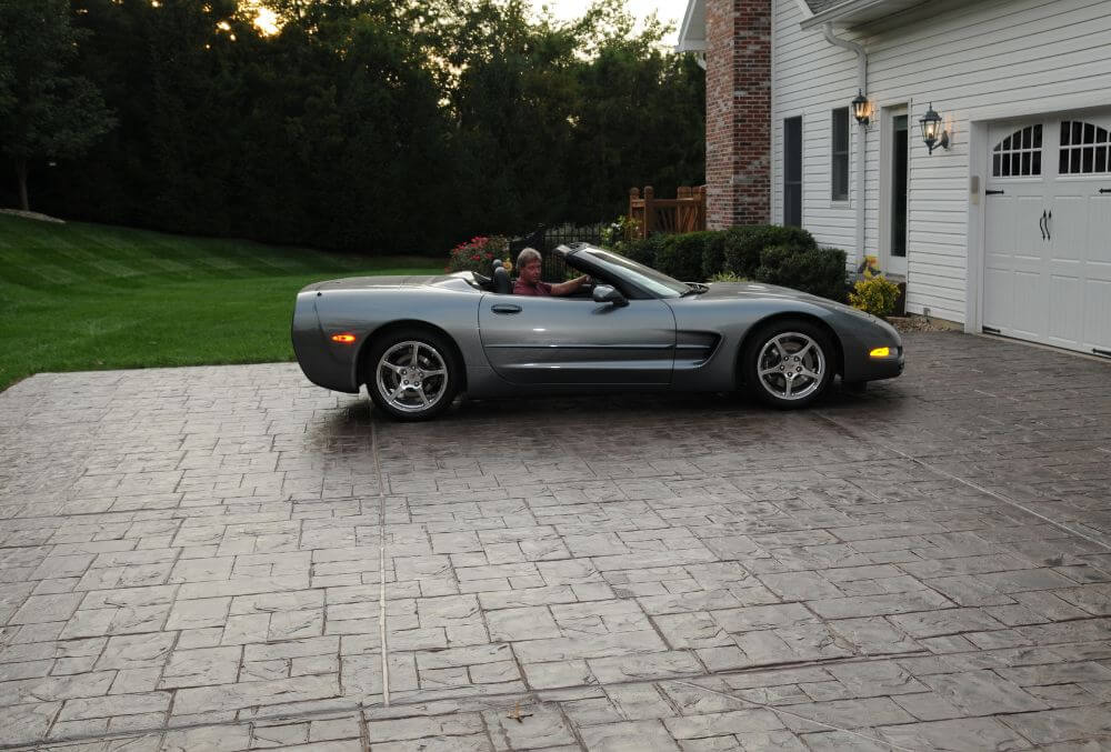 Gray stained concrete driveway with black car parked