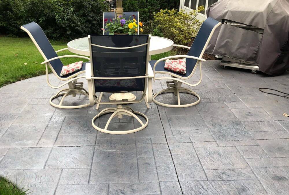 Gray stained and stamped patio with a table and chairs set