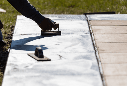 Construction worker smoothing wet cement with concrete edger