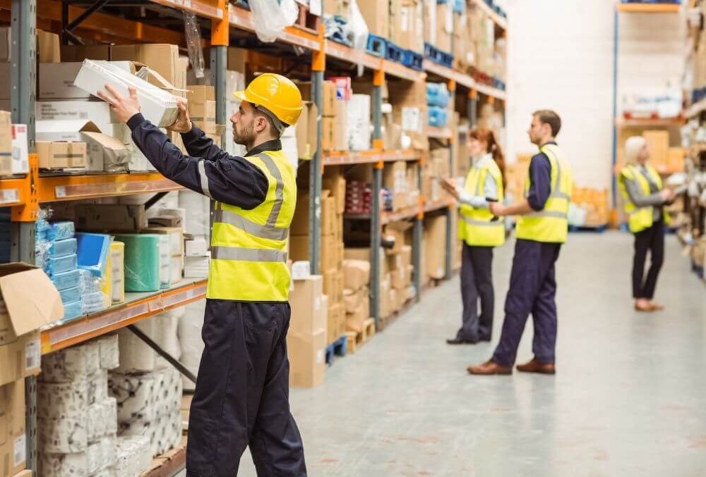 men working on in a warehouse carrying boxes