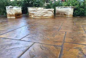 Stained concrete patio with a rich brown color and textured stone pattern, creating a durable and stylish outdoor surface.