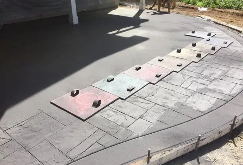 Stamped concrete overlay installation with patterned mats applied to fresh concrete for a durable decorative finish