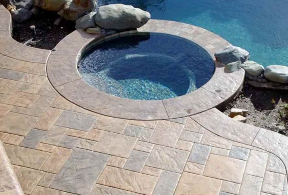 Stamped concrete pool deck with textured stone pattern, slip-resistant sealed surface, and decorative color finish for a durable, stylish outdoor space